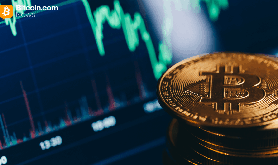 Close-up of a gold Bitcoin token sitting in front of a blurry green and black candlestick data screen.