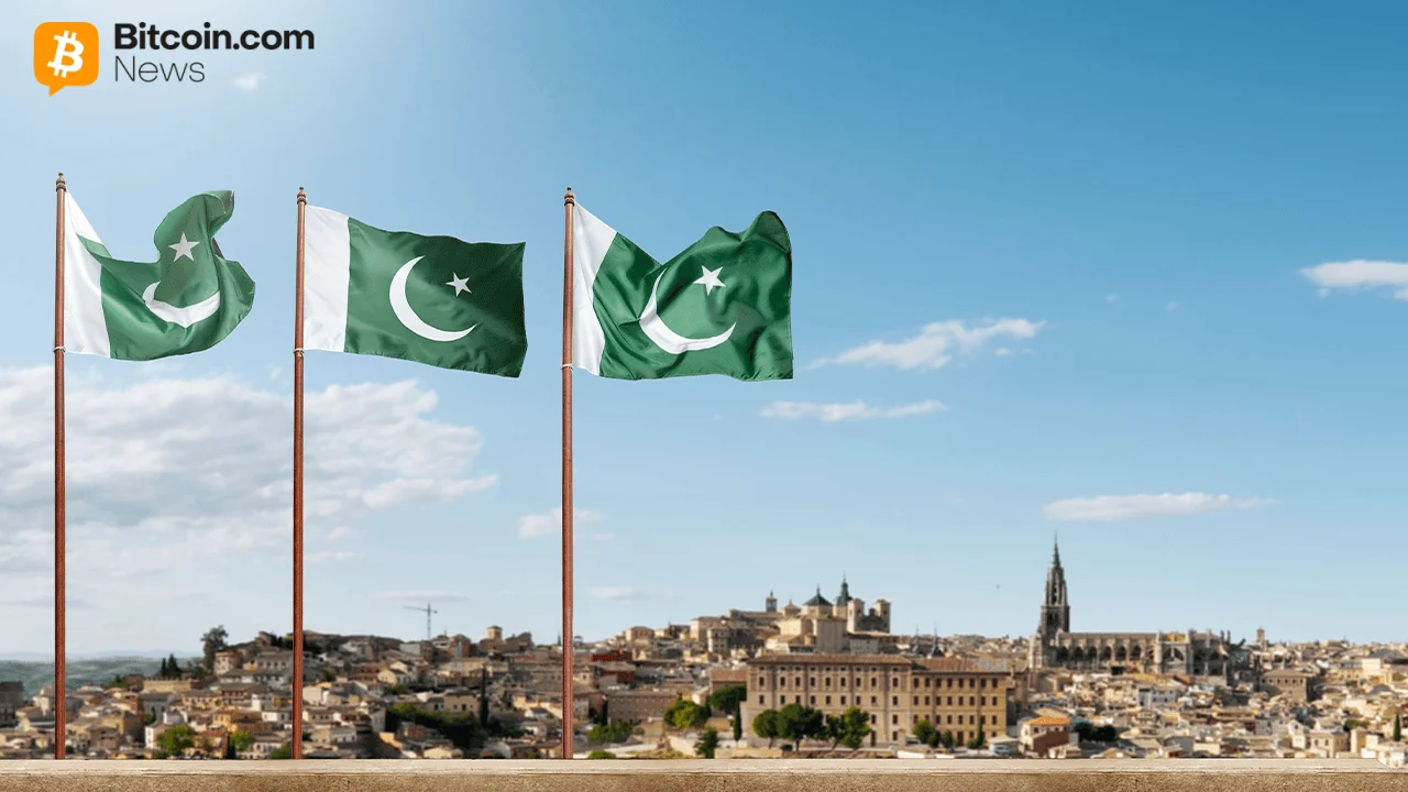 Two national flags of Pakistan fluttering side-by-side against a bright blue sky with light clouds.