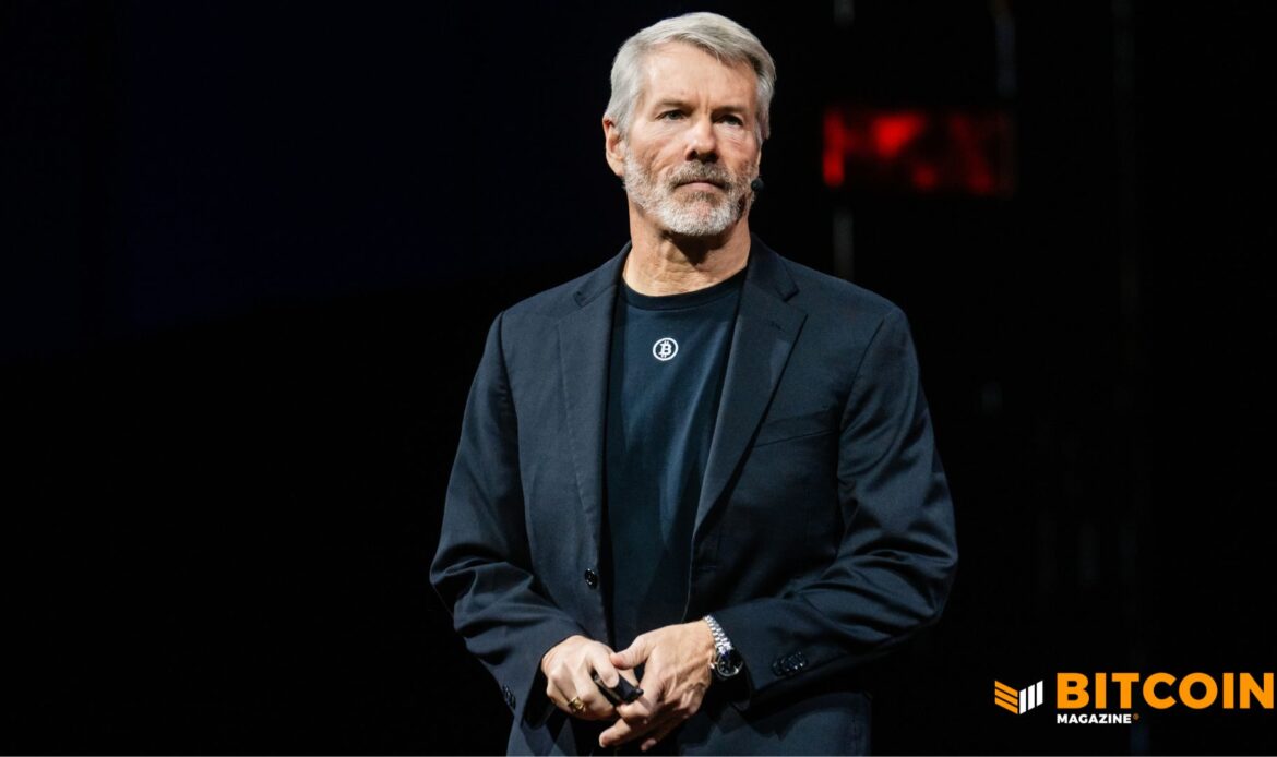 MicroStrategy founder Michael Saylor standing onstage at a tech conference, talking into a microphone in front of a dark backdrop.